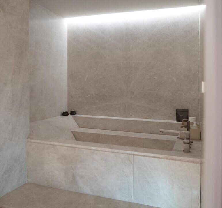 Bañera a medida realizada con estructura de WEDI y revestimiento en cuarcita Taj Mahal. Encimera con lavabos integrados.