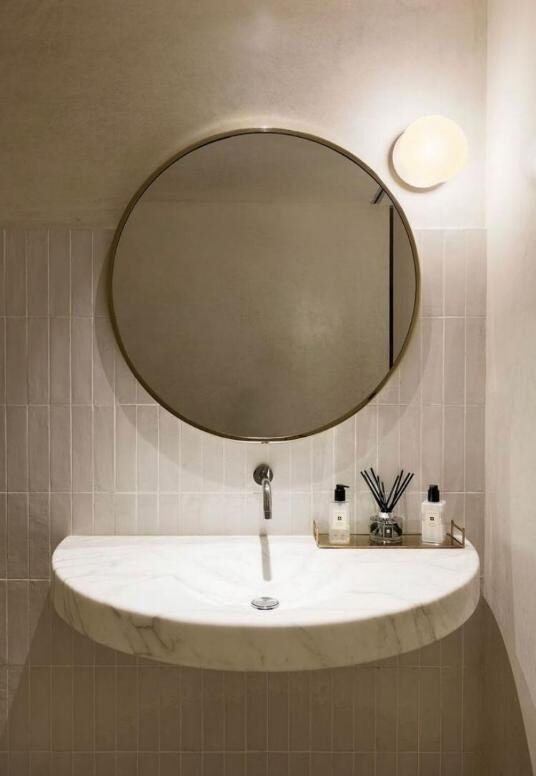 Sobre recepción en Marrón Emperador, lavabo macizo en Calacatta y aplacado baño en Verde Borgogna.