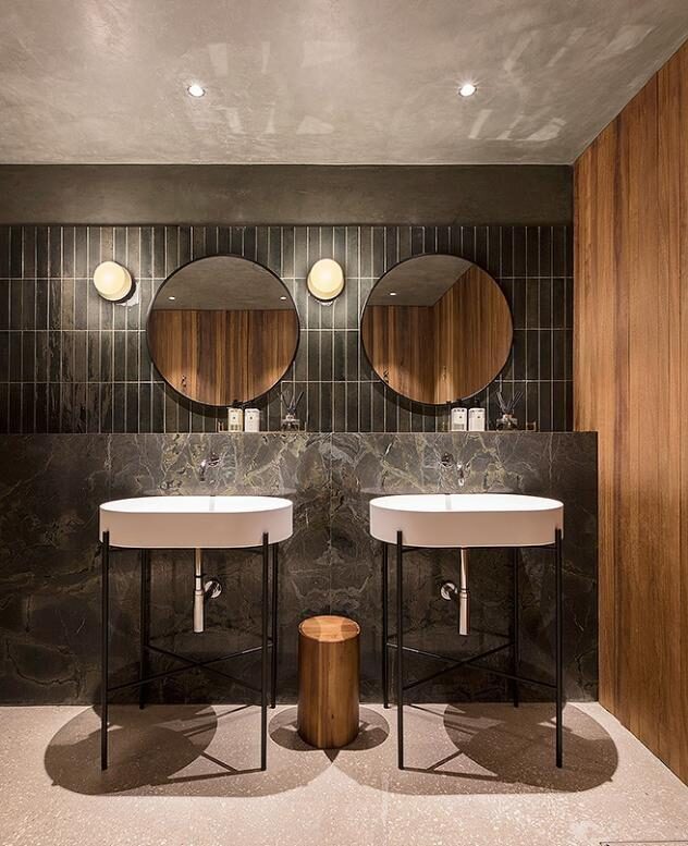 Sobre recepción en Marrón Emperador, lavabo macizo en Calacatta y aplacado baño en Verde Borgogna.